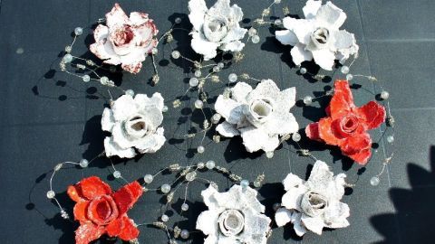 Dekorosen aus Eierkartons liegen auf schwarzer Fläche, umgeben von Perlenlichterkette, DIY-Deko in Weiß und Rot.