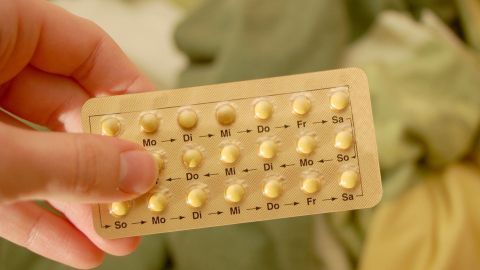 Eine Hand hält eine Blisterpackung mit Antibabypillen. Die Tabletten sind nach Wochentagen geordnet, Hintergrund unscharf.
