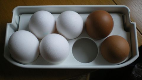 Sechs Eier liegen in einem Halter: drei weiße, drei braune. Sie eignen sich zum Vergleichen von frischen und alten Eiern.