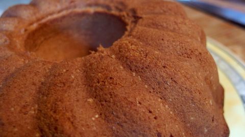Ein Cola-Kuchen steht auf einem Teller, frisch gebacken und noch warm, mit einer goldbraunen, leicht glänzenden Oberfläche.