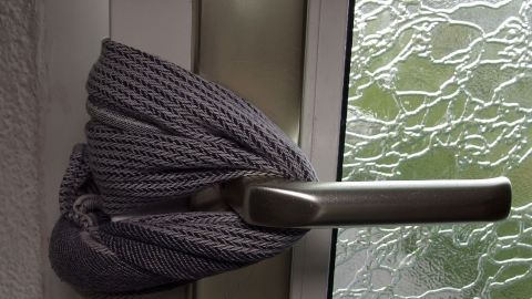 Ein graues Tuch ist um einen Türgriff gewickelt, um zu verhindern, dass Kleinkinder sich die Finger quetschen.