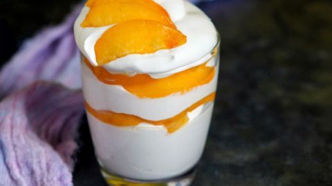 Eine cremige Nektarinen-Schichtcreme mit Amaretto ist in einem Glas geschichtet und mit frischen Nektarinenstücken garniert.
