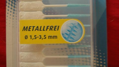Perlodent Interdental-Sticks in transparent Verpackung, metallfrei, für Zahnreinigung, auf rotem Hintergrund. Text: "MIT ETUI Ø 1,5-3,5 mm".