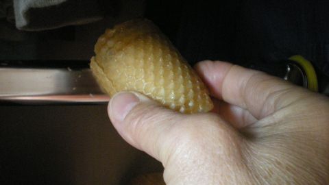 Eine Hand hält einen Waffelbecher, der auf eine Kleiderstange geschoben wird, um ein geräuscharmes Bügeln zu ermöglichen.