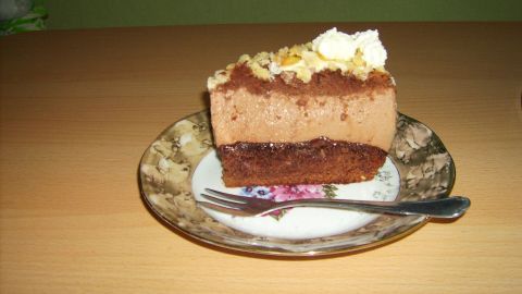 Ein Stück Schoko-Käsesahne-Torte liegt auf einem dekorativen Teller, während eine Gabel daneben wartet, um es zu genießen.