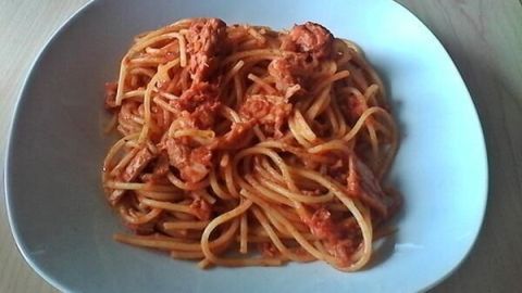 Spaghetti mit Thunfisch und Chili liegen appetitlich auf einem weißen Teller, umgeben von Holzoberfläche, bereit zum Genießen.
