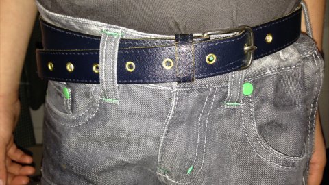 Ein blauer Gürtel hält die Hose eines Trägers an, während er in einem ungezwungenen Umfeld steht.