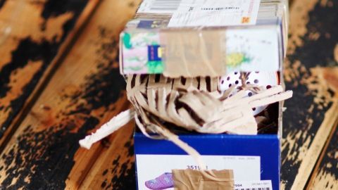 Ein Schuhkarton ist sorgfältig gepackt und mit Klebeband gesichert, um Päckchen im Innenraum zu versenden.