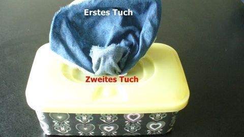 Ein Verpackungsbehälter zeigt antibakterielle Tücher, eins ist sichtbar und das andere teilweise hervorgezogen.