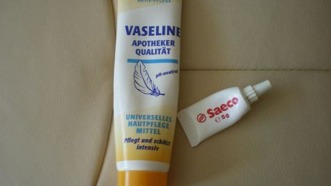 Ein Vaseline-Tube und eine kleine Saeco-Reparaturtube liegen auf einer beigefarbenen Oberfläche, bereit zur Anwendung und Pflege.