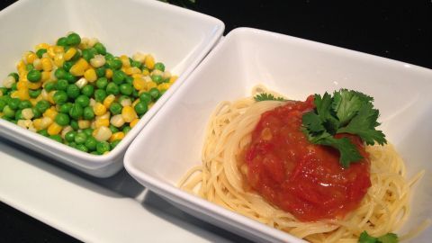 Pasta mit Tomaten-Chutney liegt appetitlich in einer Schüssel, neben einer Portion buntem Gemüse auf einem weißen Teller.