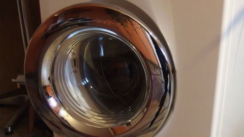 Eine Waschmaschine mit glänzendem Bullauge steht in einem Raum, bereit zum Verschenken von gebrauchten Möbeln.