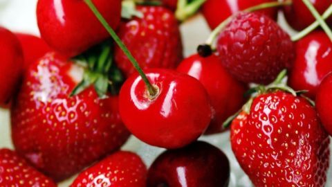 Frische, glänzende rote Erdbeeren und Kirschen liegen zusammen auf einer helle Oberfläche, bereit, Fruchtfliegen lebend zu fangen.