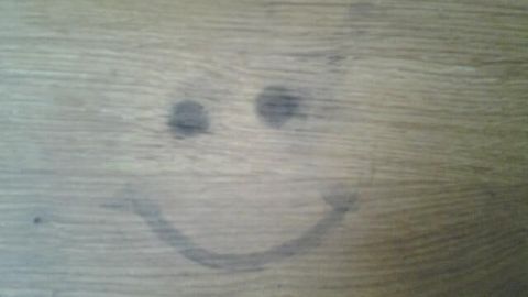 Eine Holzarbeitsplatte zeigt einen lächelnden Smiley, der durch einen Fleck entstanden ist, in einer modernen Küche.