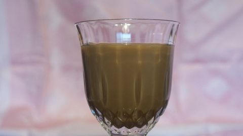 Ein stilvoller Glasbehälter mit hausgemachtem Bailey-Likör, der in sanftem Licht vor einem neutralen Hintergrund steht.