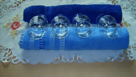 Ein klarer Glasteller steht auf einer Tischdecke, während fünf Schalen auf blauen Handtüchern arrangiert sind.