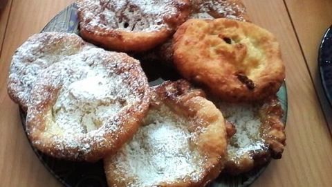 Krapfen liegen auf einem Teller, leicht mit Puderzucker bestäubt, und laden zum Verzehr in einem gemütlichen Umfeld ein.