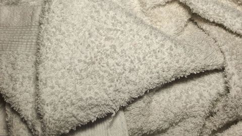 Weißes, leicht verschmutztes Textil liegt zusammengerollt, während es darauf wartet, von einem Grauschleier befreit zu werden.