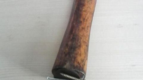 Ein Hammer mit einem langen, hölzernen Griff liegt auf einer flachen Holzoberfläche, bereit zum Arbeiten mit Nägeln.