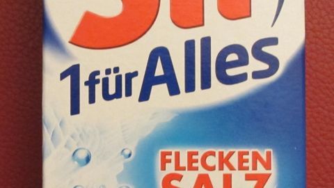 Eine blaue Verpackung von Sil 1-für-Alles-Flecken-Salz zeigt die vielseitige Anwendung als Universal-Fleckentferner. Text: "TESTSIEGER", "Alle Flecken*", "Alle Farben", "Alle Temperaturen".