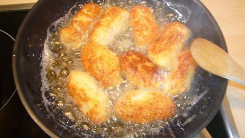 Kleine, goldbraune Blumenkohlröschen braten in einer Pfanne mit Öl, umreste verwerten in einer modernen Küche.