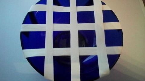 Eine runde, blaue Schale mit einem weißen Gittermuster zeigt eine einfache Anordnung für Blumen.