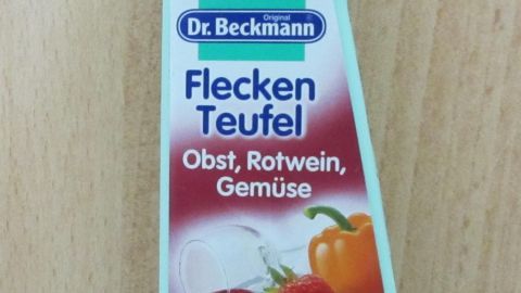 Eine Flasche Dr. Beckmanns Fleckenteufel steht auf einem hellen Tisch. Sie behandelt Flecken von Obst, Rotwein und Gemüse.