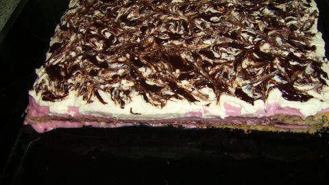 Ein großer Blechkuchen mit einer Schicht aus Quark-Mascarpone und Beerenpudding, darin eine schokoladige Verzierung.