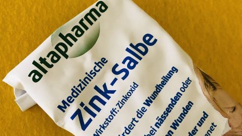 Eine Tube Zink-Salbe liegt auf einer gelben Unterlage, fördert die Wundheilung und ist auch für Kinder geeignet.