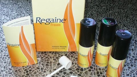 Regaine-Fläschchen stehen auf einem Tisch, während eine Anleitung daneben liegt, um gegen Haarausfall bei Frauen zu unterstützen.