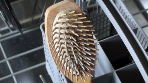 Eine Haarbürste liegt in einer Spülmaschine, während der Reinigungsprozess in einem modernen Küchenraum stattfindet.