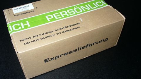 Eine braune Versandbox mit einem grünen Etikett, auf dem "Persönlich" steht, wird als persönliche Lieferung erkannt.