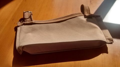 Eine praktische Gürteltasche liegt auf einem Holztisch und reflektiert Sonnenlicht, während sie bereit zum Einsatz ist.