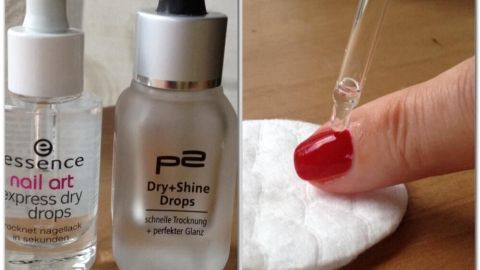 Zwei Fläschchen mit speziellen Tropfen zur Nagellack-Trocknung stehen neben einem Wattepad, während ein Finger mit rotem Nagellack darauf zeigt.