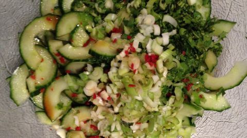 Frisch geschnittener Gurkensalat liegt in einer Schüssel, gemischt mit Kräutern und frischen Zutaten.