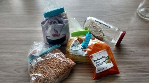 Verschiedene Lebensmittelverpackungen liegen auf einem Tisch und zeigen Tipps für einen ersten Haushalt durch die Auswahl an Vorräten.