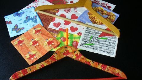 Bunte Holzkleiderbügel liegen auf einem Tisch, umgeben von dekorativem Papier, bereit zum Verschönern und Gestalten.
