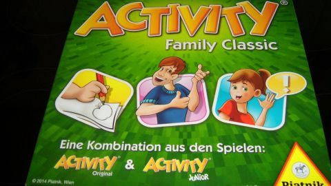 Die Spieleschachtel "Activity Family Classic" zeigt fröhliche Spieler, die aktiv teilnehmen und kommunizieren. Sie steht vor einer grünen Hintergrundgestaltung.