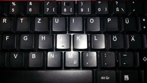 Eine verklebte PC-Tastatur mit hervorgehobenen Tasten zeigt Schmutz und Ablagerungen, die dringend gereinigt werden müssen.