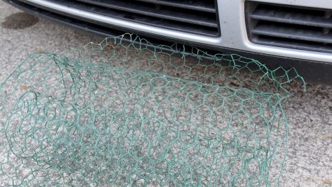 Ein Drahtgeflecht liegt vor einem Fahrzeug, um Marderschäden vorzubeugen und den Unterboden zu schützen.