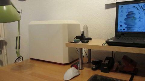 Auf einem Tisch steht eine Nähmaschine, die bereit ist, genutzt zu werden, während ein Laptop daneben Licht spendet.