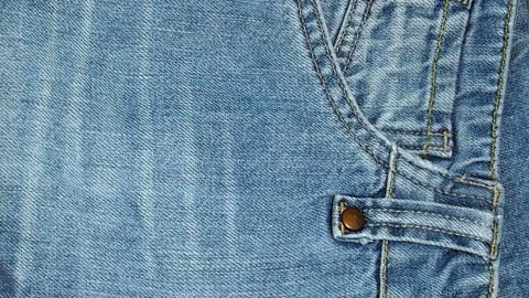 Ein blauer Jeansstoff mit einer daneben sichtbaren Knopfleiste und Taschen zeigt eingetrocknete Blutflecken.