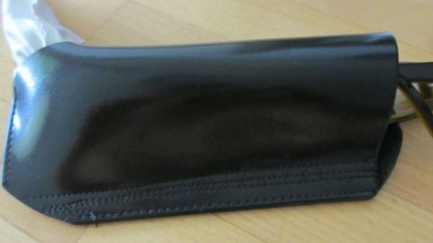 Ein schwarzes Brillenetui liegt auf einem Holzuntergrund, während es darauf wartet, eine neue Brille sicher zu verwahren.