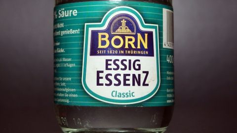 Ein Glas-Essigessenz steht auf einem dunklen Hintergrund, bereit zur Anwendung gegen Marderschäden in Fahrzeugen.