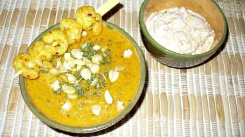 Eine goldene Möhren-Ingwer-Linsensuppe wird mit knusprigen Garnelen und einer kleinen Schale Joghurt serviert.