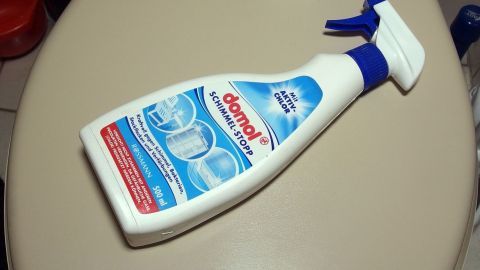 Auf einer Toilettenoberfläche liegt eine Flasche Schimmelentferner, bereit zum Urinstein entfernen in einem Badezimmer.