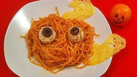 Ein Teller mit Spaghetti ist zu einer gruseligen Figur geformt, mit Oliven als Augen und knusprigen Geistern als Flügel.