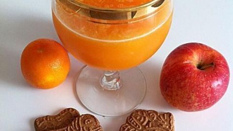 Ein frischer Clementinen-Apfel Smoothie ist in einem eleganten Glas mit Zierde serviert, umgeben von Äpfeln und Keksen.
