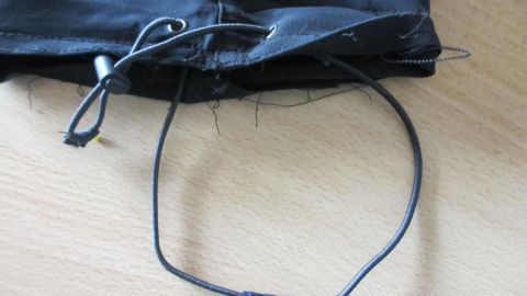 Eine schwarze Sporthose mit runden Bändern, die nebeneinander verbunden sind, liegt auf einem Tisch.