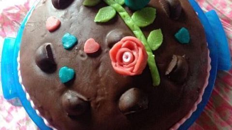 Eine runde Schoko-Mozartkugeltorte mit bunten Zuckerdekorationen liegt auf einem blauen Tortenteller in einem ansprechenden Umfeld.